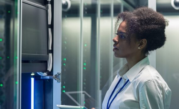 A woman holding a tablet in front of a server.