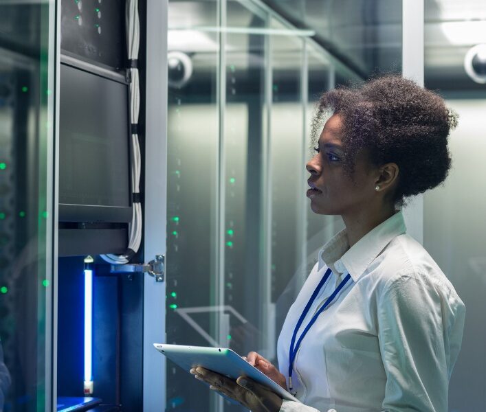 A woman holding a tablet in front of a server.