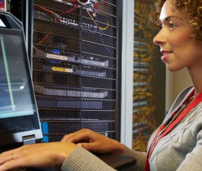 A woman sitting at her computer desk looking at the screen.