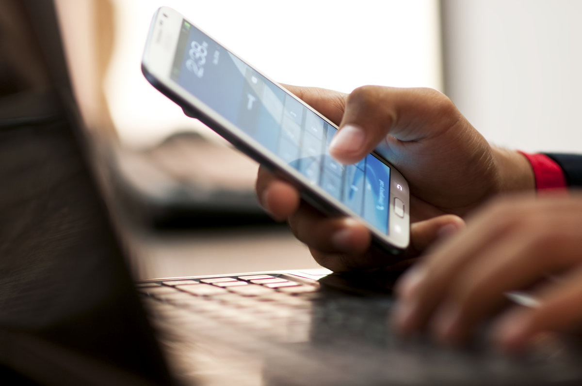 A person is using their cell phone on the keyboard