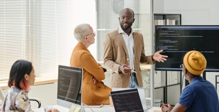 A man and woman are standing in front of laptops.