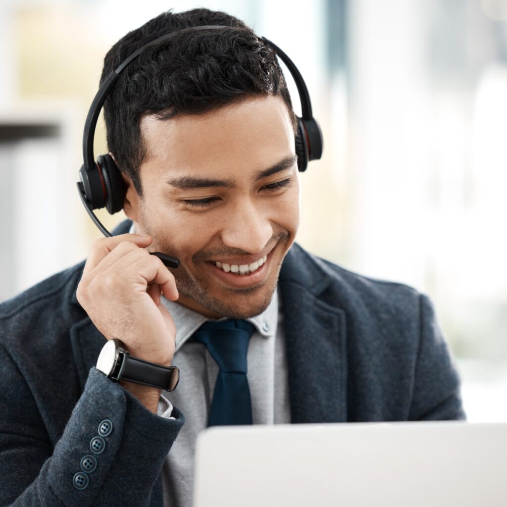 A man wearing headphones while looking at his laptop.