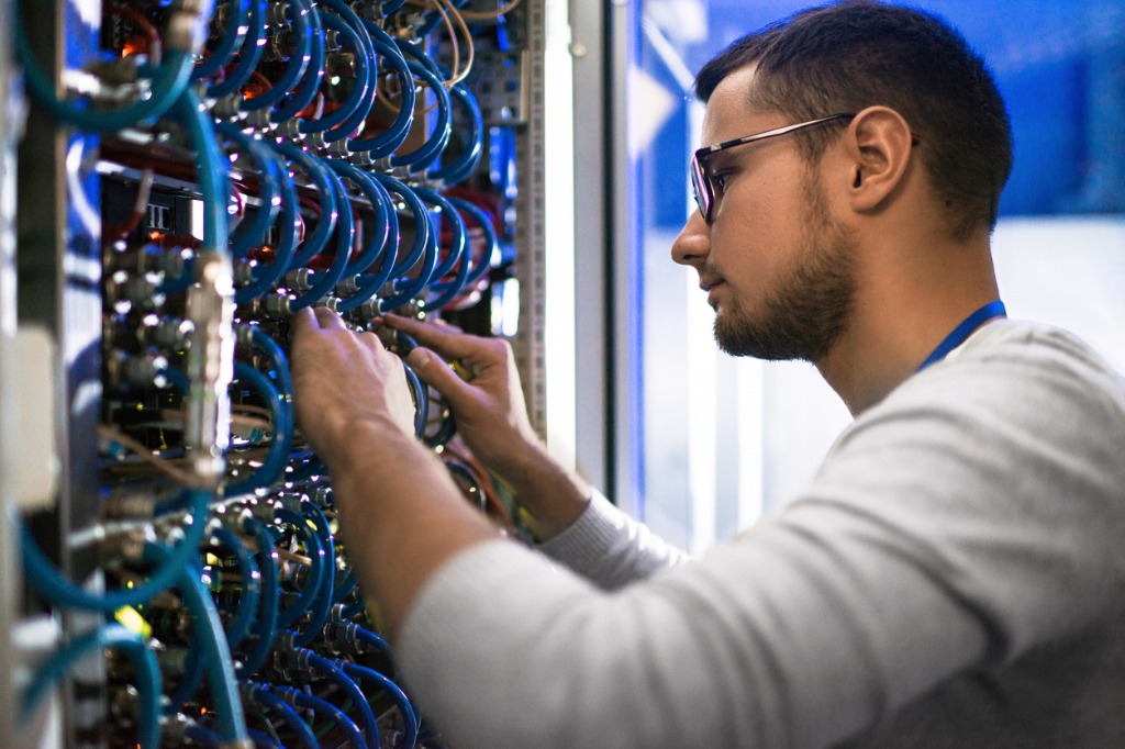 A man working on some wires in the middle of a room.