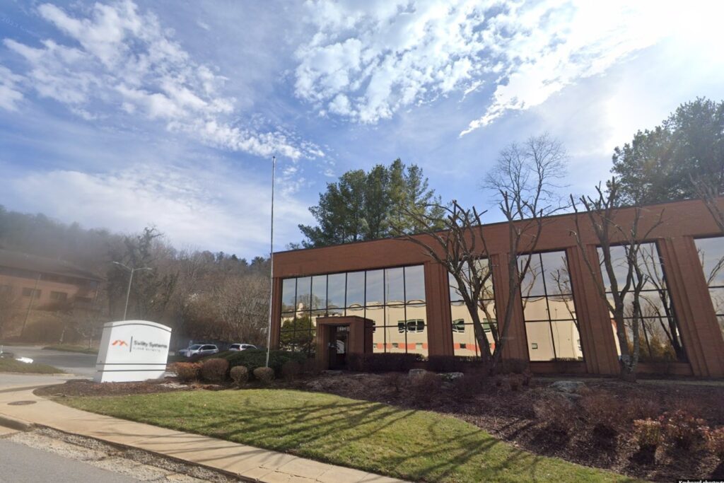 A building with trees and bushes in front of it.