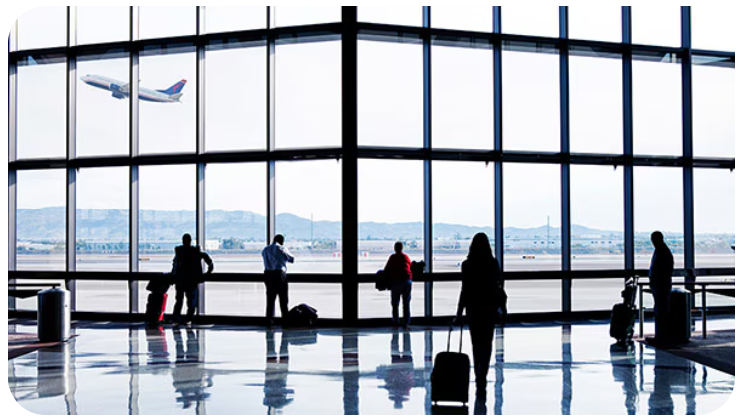 A group of people standing in front of an airport window.