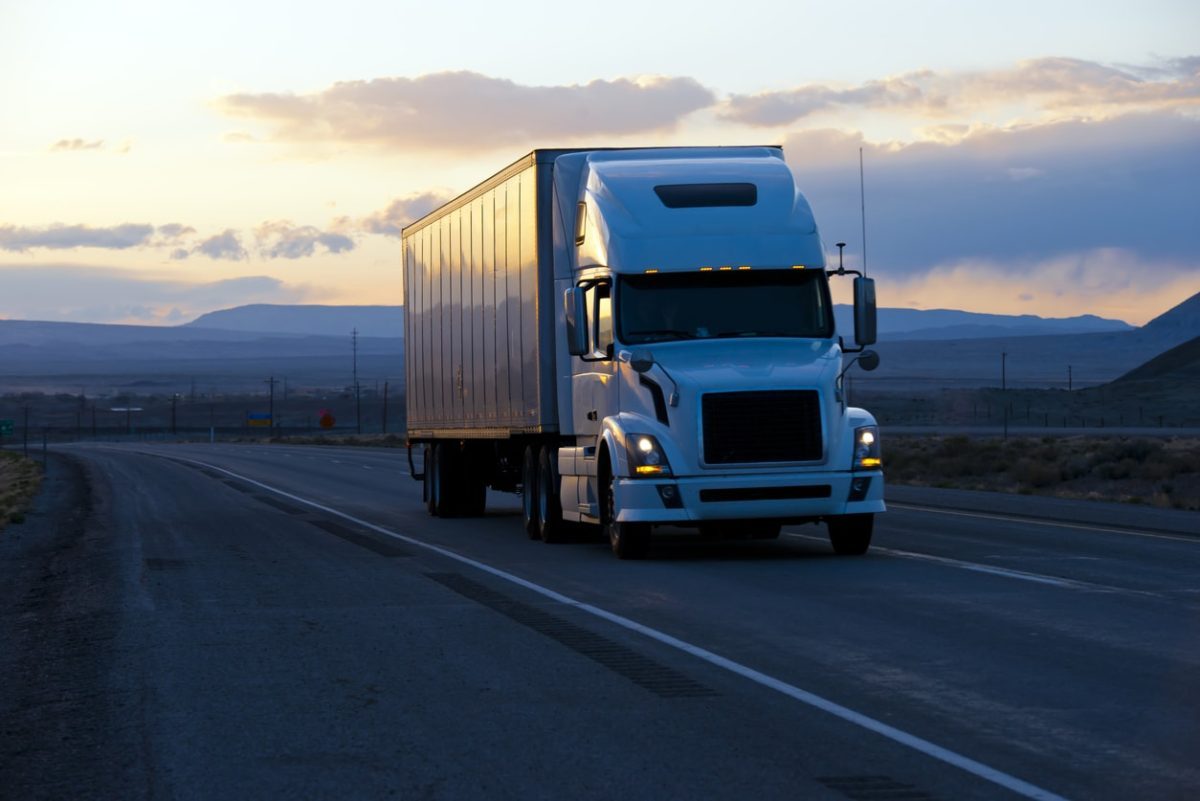 A semi truck is driving down the road.